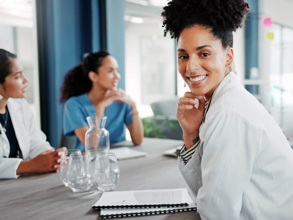 A smiling medical professional in a meeting with two of her colleagues - Stroudwater